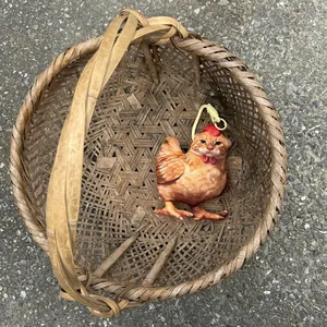 Vista detallada de un divertido llavero de peluche de gato-pollo en una cesta