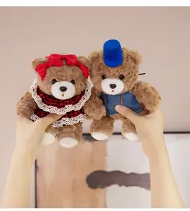 Detailed shot of two small brown teddy bears with cute outfits held in hands as a gift
