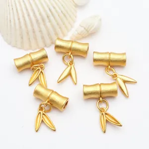 Detailansicht von mattgoldenen Bambusblatt-Anhängern für die Herstellung von DIY-Schmuck.
