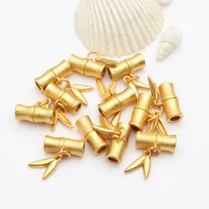 Detailansicht matter goldener Perlen in Bambusform mit Blattanhängern für DIY-Schmuck