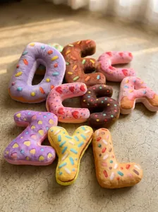 Variedad de cojines de peluche con letras del alfabeto y diseño de donuts.