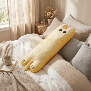 Détail d'un long oreiller en peluche en forme de chat jaune à carreaux sur un lit.