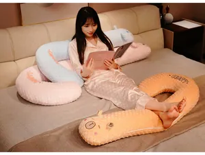 Femme se relaxant sur un lit avec un long oreiller de corps souple en forme de U