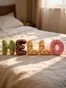 Cojines de letras de peluche tipo donut que forman HELLO en una cama.