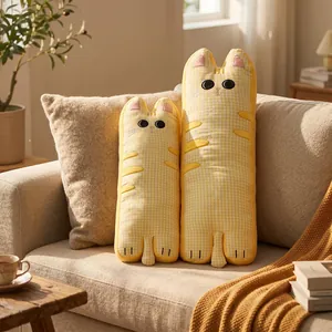 Paire de jolis coussins longs en forme de chat à carreaux jaunes sur un canapé