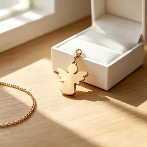 Detailansicht eines goldfarbenen Edelstahl-Engelsanhängers an einer weißen Geschenkbox