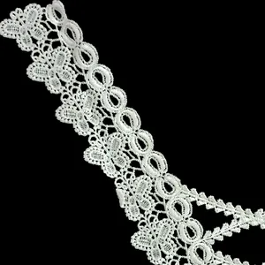 Detail view of white embroidered polyester lace with intricate butterfly and oval patterns