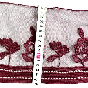 Detail view of burgundy floral embroidered lace trim with measuring tape for width
