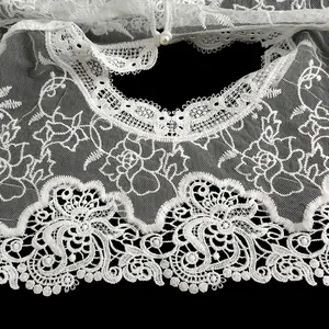 Gros plan d'un châle en dentelle brodée blanche avec des motifs floraux très détaillés.