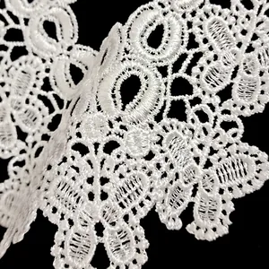 Detailed macro shot of white polyester embroidered lace trim with hollow floral patterns