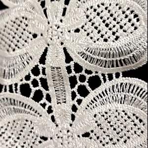 Detailed macro view of white polyester hollow embroidered lace trim for clothing