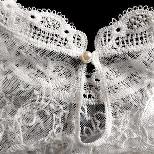 Gros plan macro sur dentelle brodée florale blanche avec bouton perle central