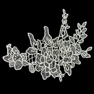 Detailed view of intricate white floral lace applique with embroidery on black background
