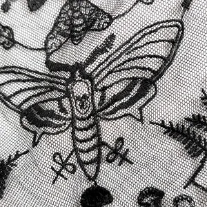 Nahaufnahme von schwarzer Spitzenstickerei mit detailliertem Mottenmuster für Kleidung.