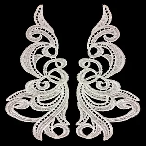 Close-up of white water-soluble lace patches with symmetrical scroll embroidery