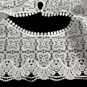 Détail de broderie en dentelle de soie de lait blanche avec motifs floraux ajourés