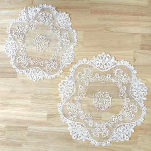 Detailed view of two white circular lace doilies with intricate embroidery on a wooden surface.