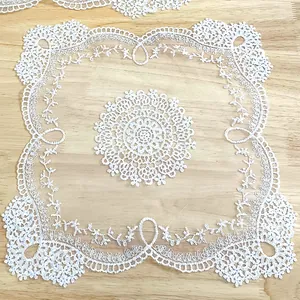 Detailed macro view of white square lace doily with intricate floral embroidery