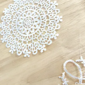 Close-up detail of delicate white floral embroidered lace pattern on mesh fabric
