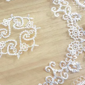 Close-up of white hollow embroidered lace table mat showing intricate floral patterns