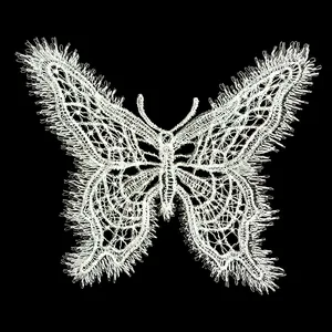 Detailed macro view of an intricate white butterfly lace embroidery applique patch on black