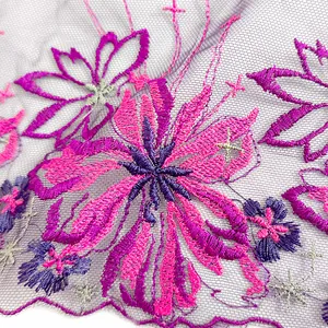 Close-up of vibrant pink and purple floral embroidery on fine purple mesh lace fabric