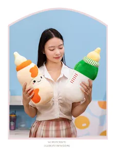 Asian female model holding two adorable baby bottle shaped plush pillows in a studio