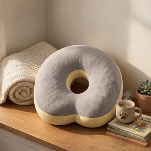 Gros plan d'un oreiller beignet en velours côtelé gris sur un bureau en bois au soleil chaud
