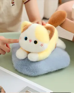 Detailed view of a soft calico cat plush toy resting on a grey faux fur cushion