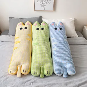 Trois longs coussins de chat mignons en tissu seersucker à carreaux colorés sur un lit.