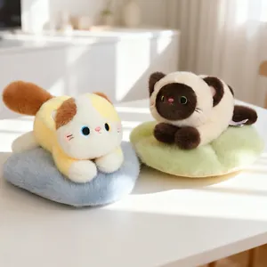 Two cute calico and Siamese cat plush toys resting on soft blue and green furry pads
