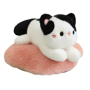 Adorable black and white cow cat plush toy resting on a soft pink heart-shaped furry cushion