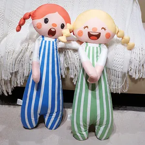 Paire de jolies poupées en peluche en salopettes rayées colorées sur un canapé