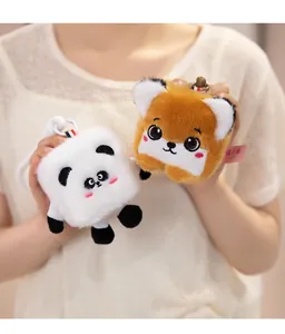Detail view of cute cube panda and brown fox plush keychains held by an Asian model
