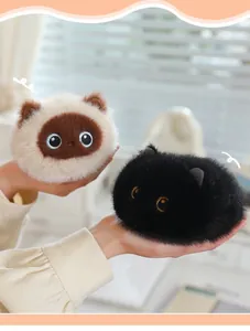 Close-up view of adorable fuzzy palm-sized Siamese and black cat plush toys held in hands.