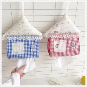 Close-up of cute house-shaped fabric tissue box covers hanging on a tiled wall