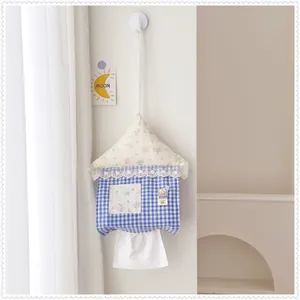 House-shaped fabric tissue hanging holder shown in a cozy minimalist bedroom scene