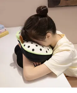 Close-up of a person resting on a cartoon polka dot apple nap pillow on a desk