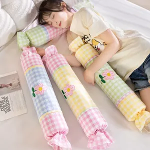 Cojín cilíndrico con forma de caramelo, cuadros de colores y flores.