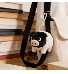 Adorable black-faced pig plush keychain accessory hanging on a white bag strap strap