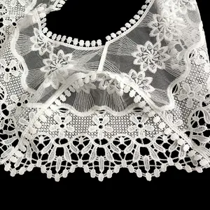 Gros plan sur le châle en dentelle brodée de soie de lait blanche aux motifs floraux