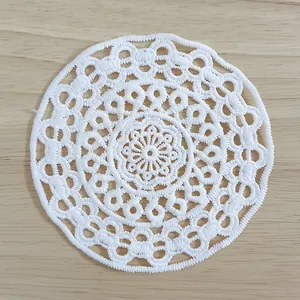 Macro view of white vintage water-soluble lace doily with intricate floral patterns.