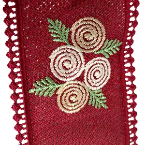 Close-up of red lace collar piece with intricate spiral flower embroidery and green leaves