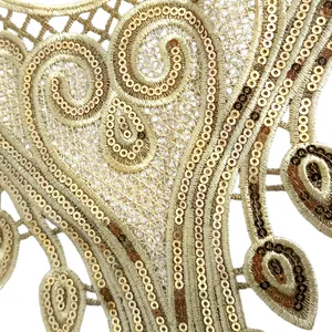 Macro detail of golden sequin lace embroidery with intricate hollow floral patterns