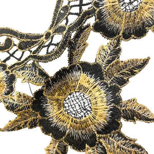 Macro detail of black and gold embroidered floral lace with intricate hollow patterns