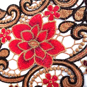 Gros plan d'une fleur rouge vive et de broderies de dentelle dorée sur un col ethnique