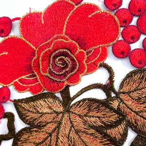 Detailed close-up of intricate red rose and grape floral embroidery with gold trim