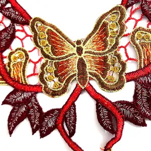 Gros plan détaillé de la broderie complexe papillon rouge et or sur col en dentelle