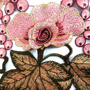 Detailed close-up of pink floral embroidered lace appliqué with gold thread edging