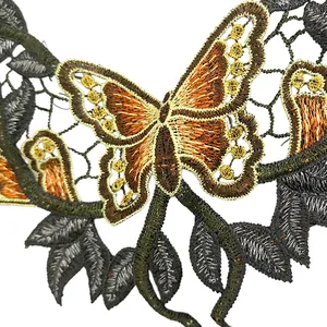 Détail de dentelle brodée avec papillon utilisant des fils verts et oranges vifs